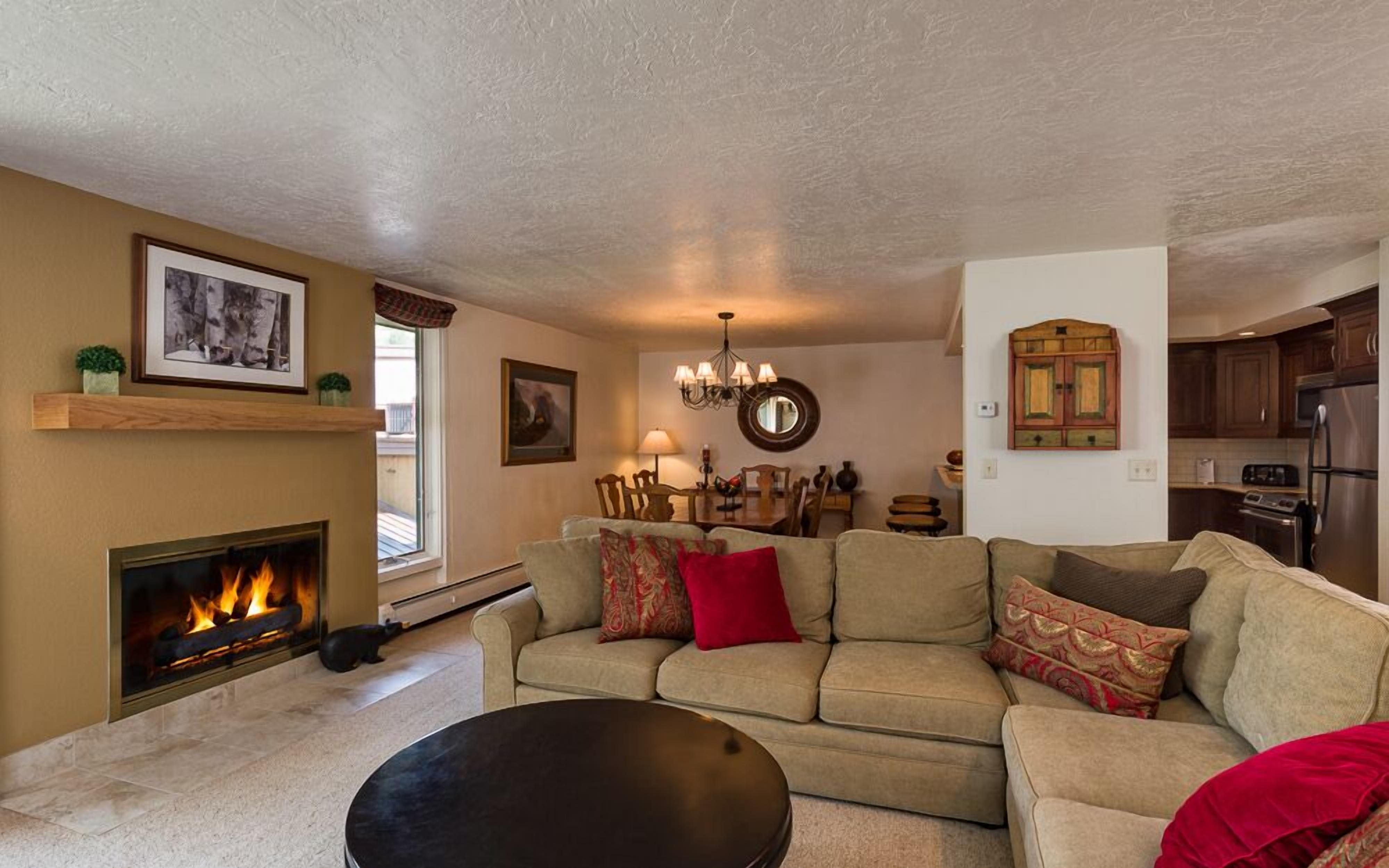 A living room with a fireplace, a dining area, and a kitchen.