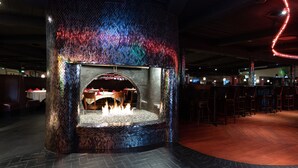 A restaurant with a unique mosaic fireplace, tables, and chairs. - Americas Best Value Inn Rancho Palos Verdes (Rancho Palos Verdes)
