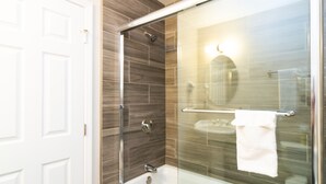 A modern bathroom with a glass shower enclosure, a glass-enclosed sink, and a white door. - Americas Best Value Inn Rancho Palos Verdes (Rancho Palos Verdes)