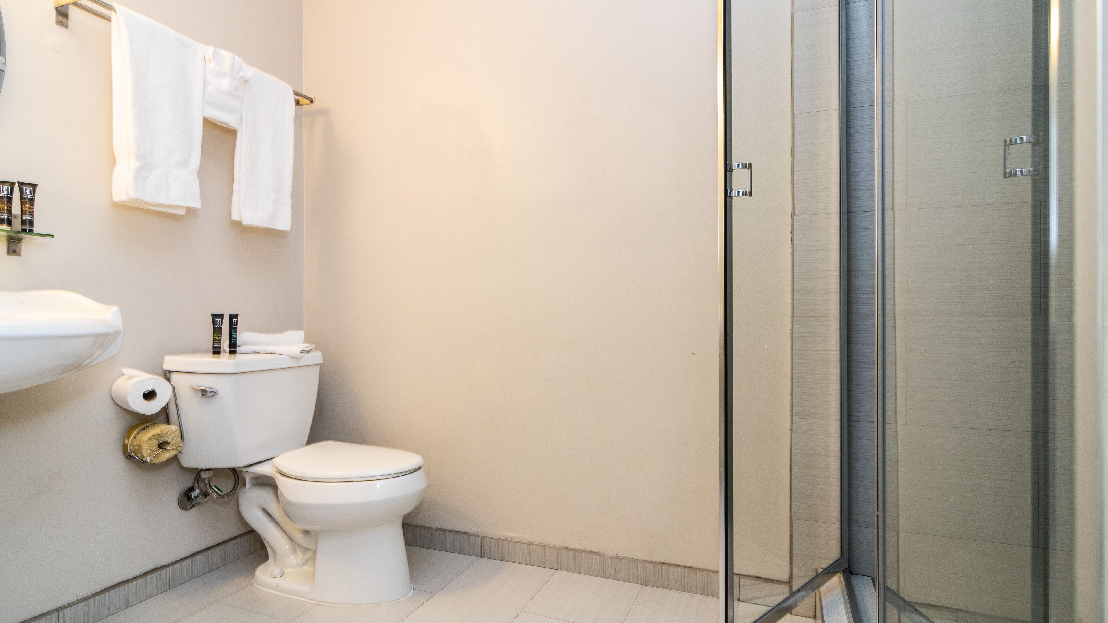Un baño moderno con inodoro, lavamanos y cabina de ducha de vidrio.