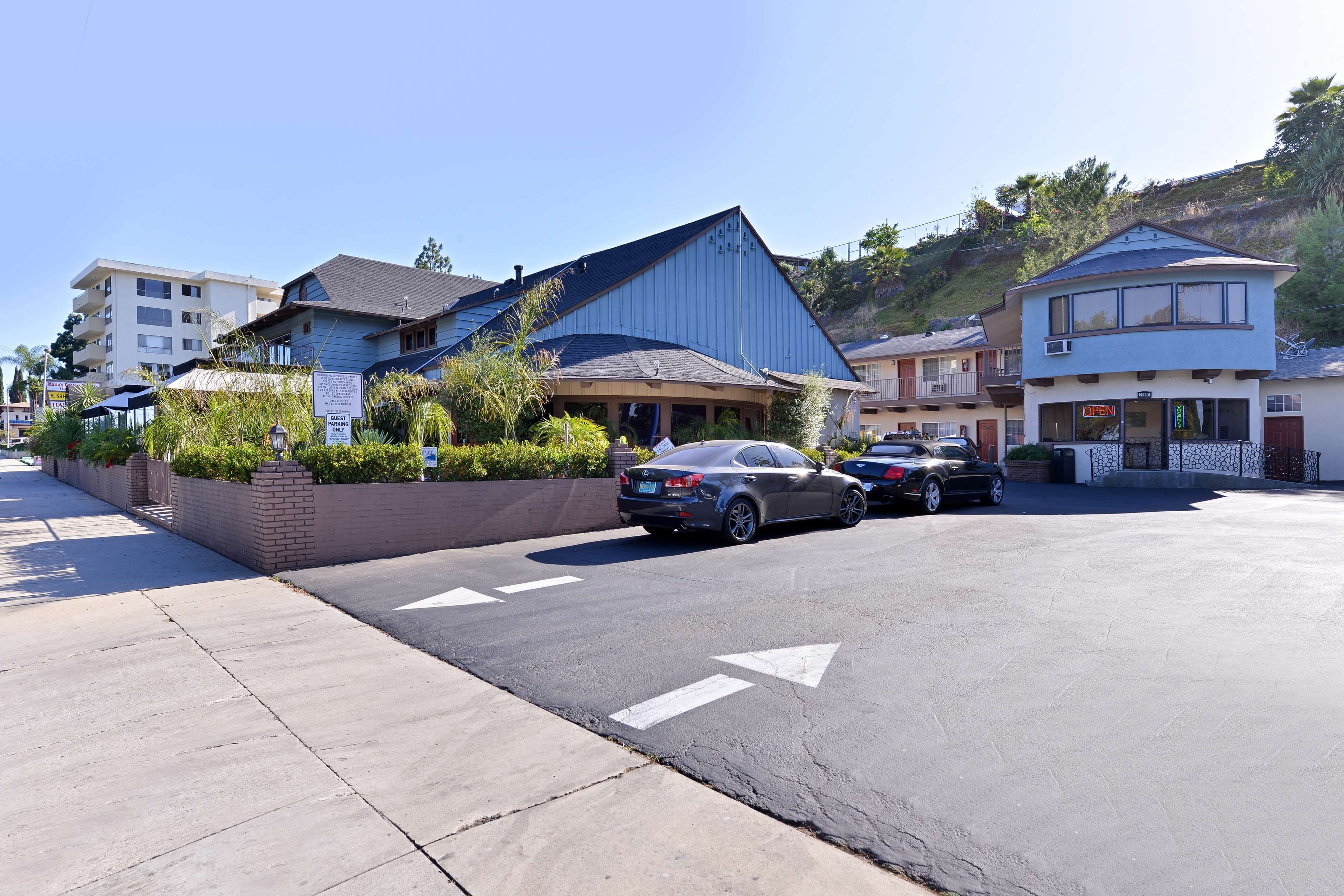 A parking lot with cars, a building with a blue roof, and a sign that says "OPEN".