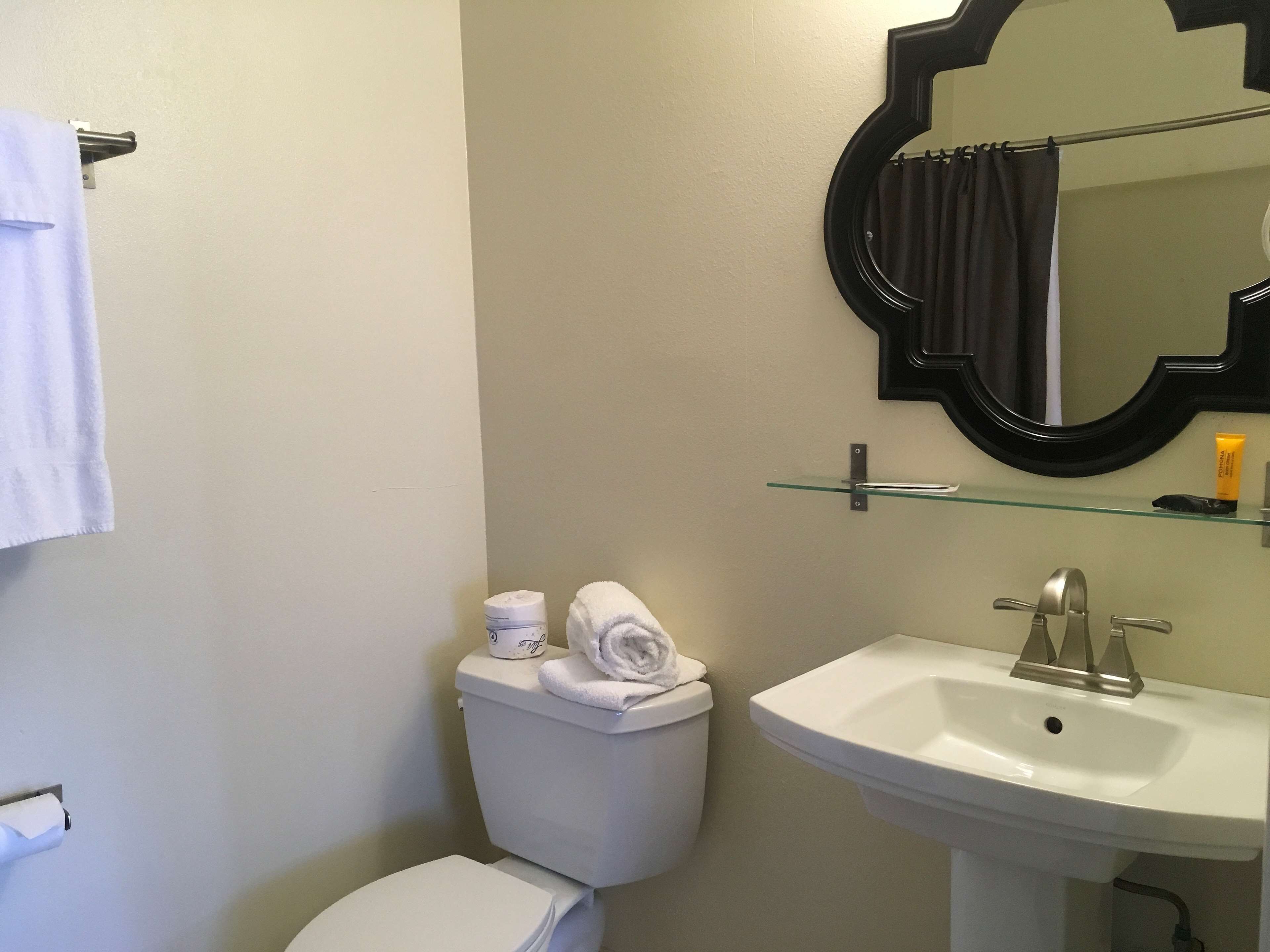 Une salle de bain comprenant des toilettes, un lavabo, un miroir et un porte-serviettes.