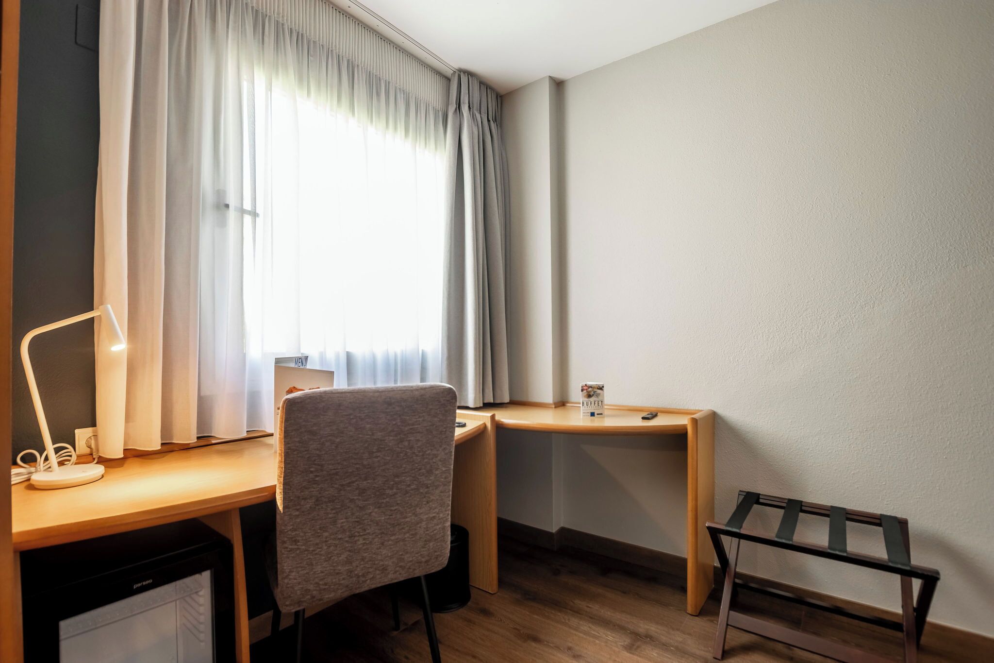 A small, neatly arranged workspace with a desk, chair, and a lamp.