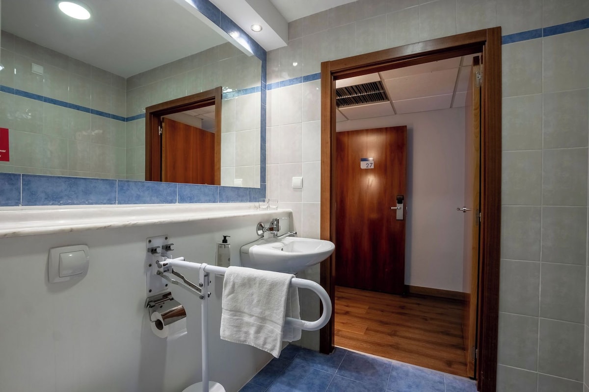 Une salle de bain avec un lavabo blanc, un miroir et un porte-serviettes.