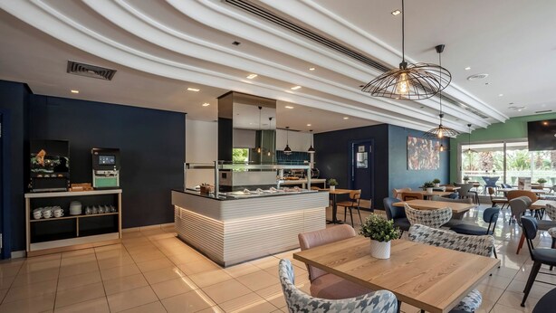 Een modern café met een centrale balie, een zitgedeelte en uitzicht op het omliggende landschap.