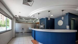 Een moderne receptiebalie met blauwe accenten, een klok en hanglampen.