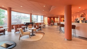 Un espace de détente moderne comprenant un piano, des sièges, un bar et de grandes fenêtres offrant une vue panoramique.