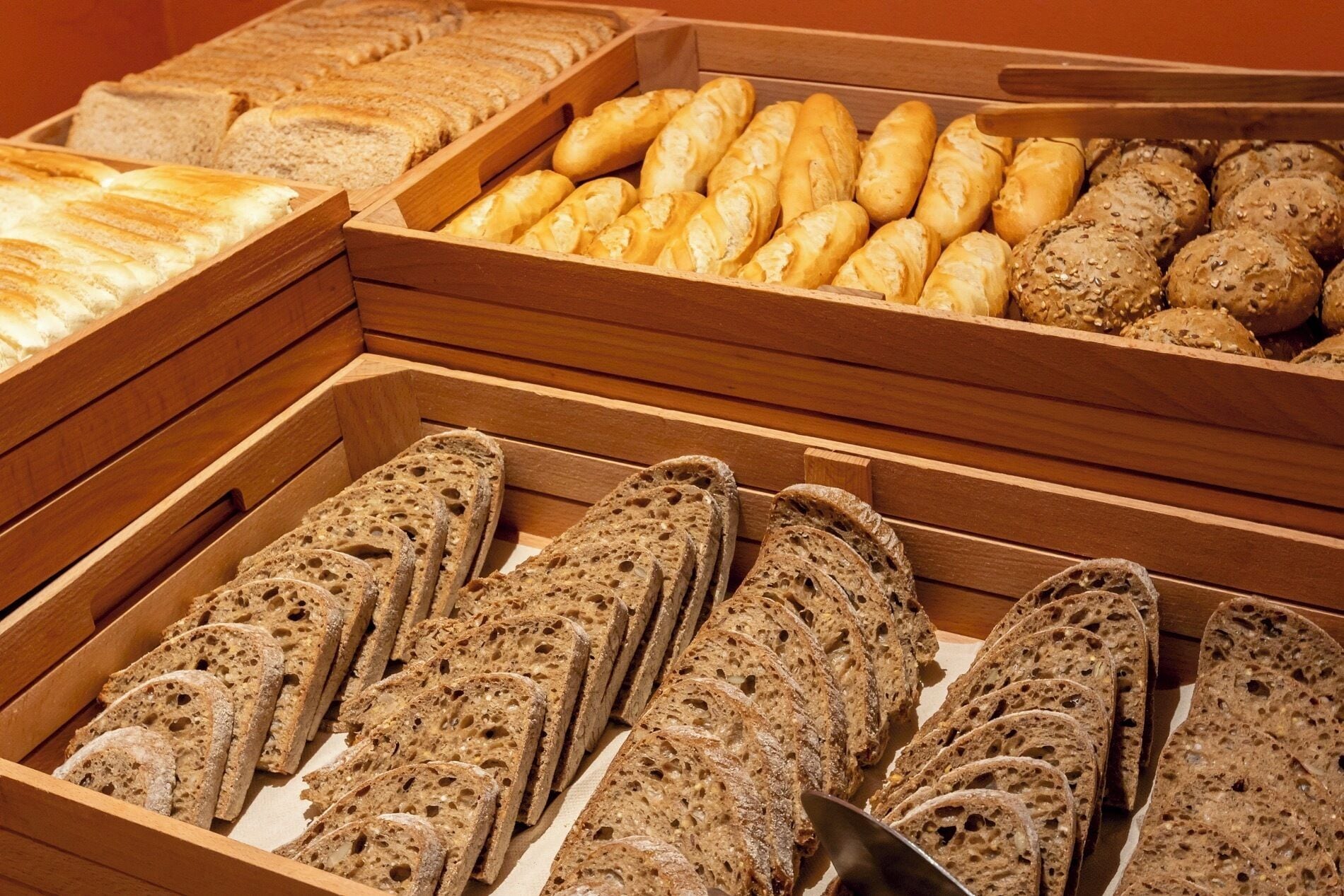 Une variété de pains et de viennoiseries présentés dans des plateaux en bois.