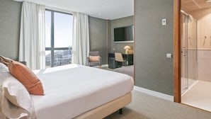 Une chambre d’hôtel avec un grand lit, un bureau avec une chaise, une télévision et un espace douche.