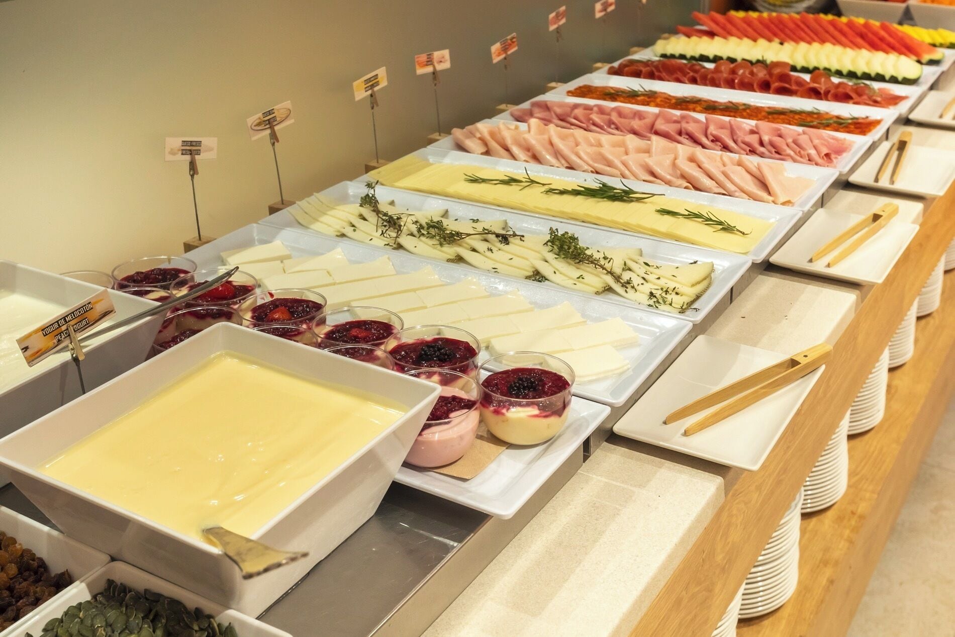 A buffet with various food options including meats, cheeses, and desserts.