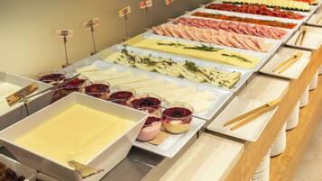 A buffet with various food options including meats, cheeses, and desserts.