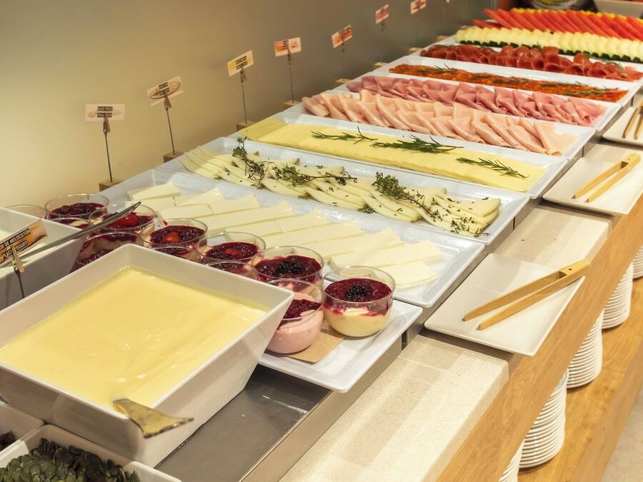 A buffet with various food options including meats, cheeses, and desserts.