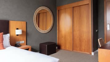 A hotel room with a bed, bedside table, lamp, and a large wooden wardrobe.