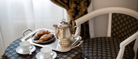 A table with a tray holding pastries, a teapot, and two cups with saucers.