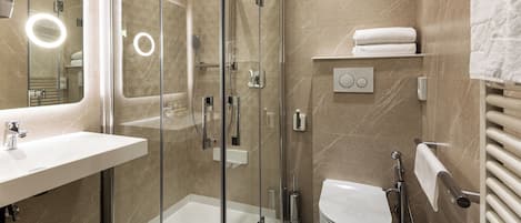 Un baño moderno con ducha de vidrio, lavamanos blanco y retrete.