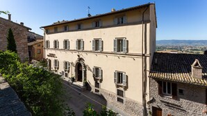 A two-story building with a stone facade, a central entrance with an archway, and multiple windows with shutters. - Hotel Fontebella (Assisi)