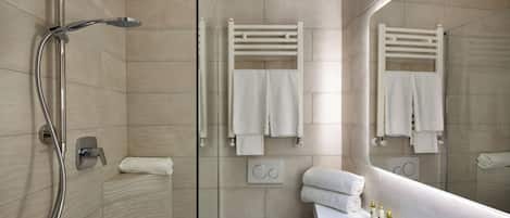 A modern bathroom with a glass-enclosed shower, a white sink with toiletries, and a large mirror reflecting the space.