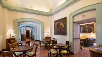 Um amplo hall de hotel com uma escadaria imponente, mobiliário de madeira e obras de arte clássicas.