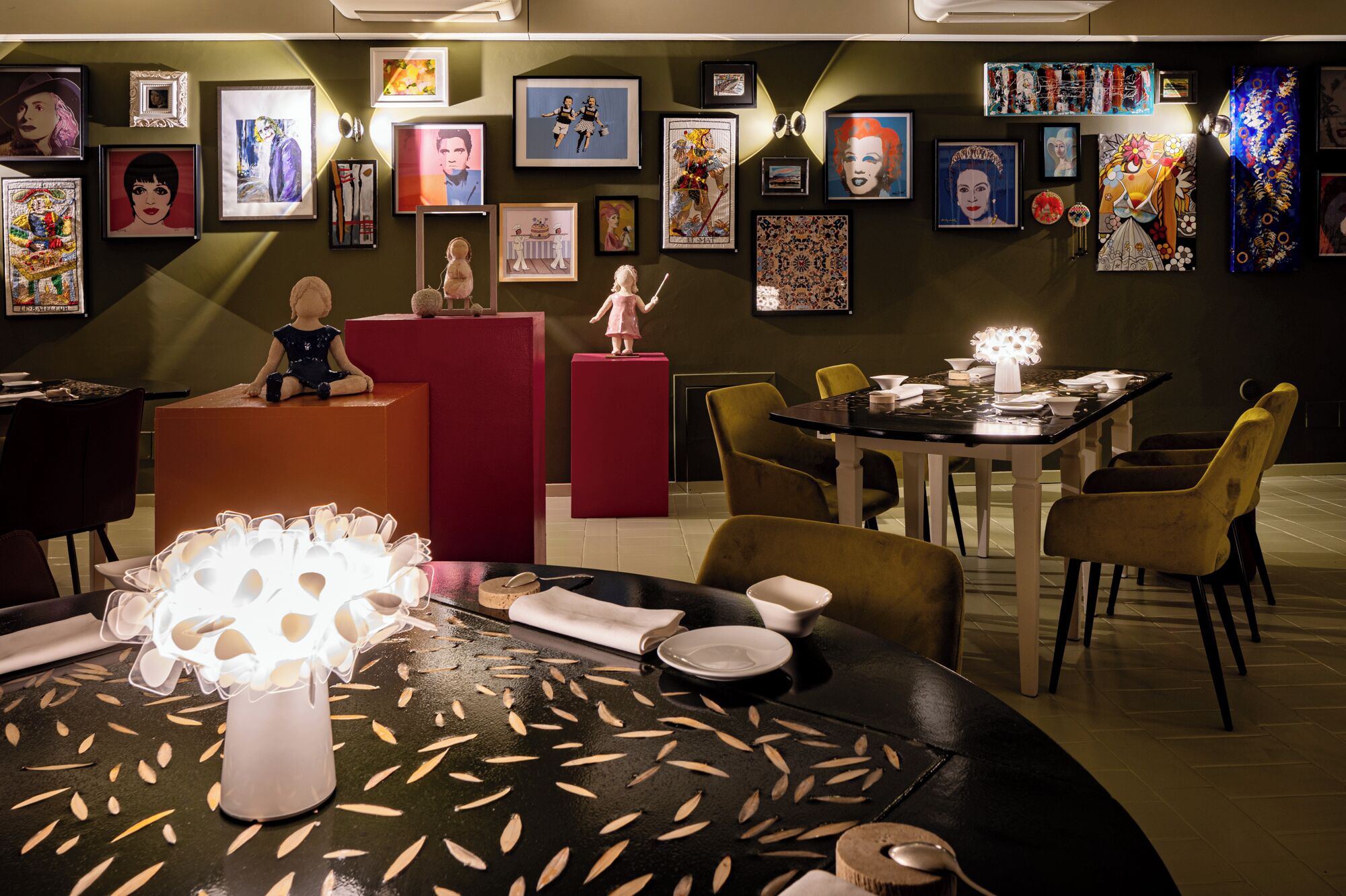 Zona pranzo con un tavolo apparecchiato per due, circondato da sedie, e una parete decorata con diverse opere d'arte incorniciate.
