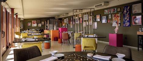 Un restaurante moderno con diversas opciones de asientos, incluyendo mesas y sillas, y una pared decorada con obras de arte.