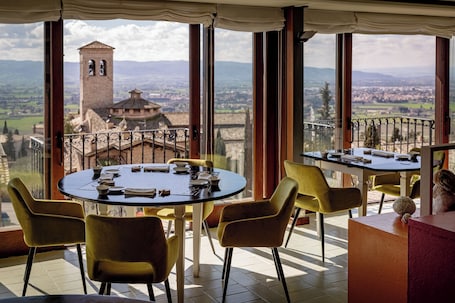 A dining area with a table set for two, overlooking a scenic view of a historic tower and landscape.