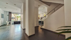 Un moderno vestíbulo de hotel con una escalera, una recepción y un área de estar.