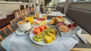 Una mesa de desayuno con platos de fruta, una taza de café y una caja de helado Helios.