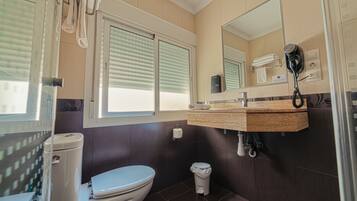 Un baño moderno con inodoro, lavamanos y secador de pelo fijado a la pared.