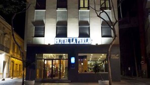 Fachada de hotel con un letrero que dice "HOTEL LA PERLA" y una entrada visible con puertas de vidrio.