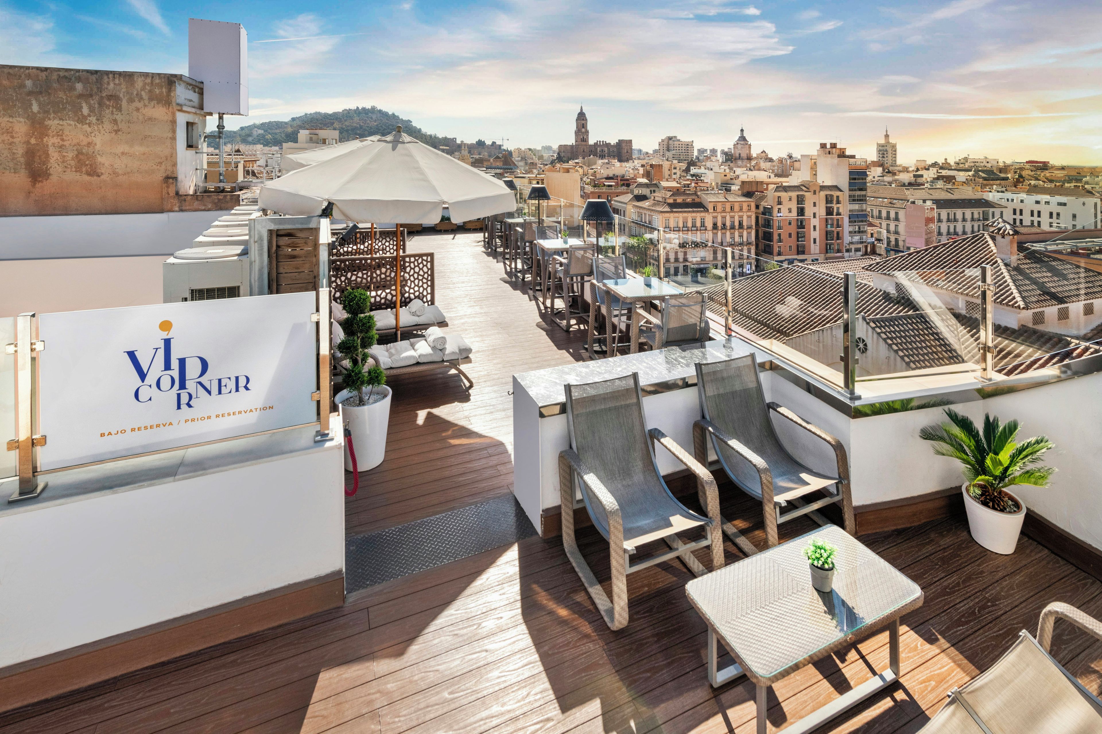 A rooftop terrace with outdoor seating, a sign for 'VOR CORNER', and a view of the cityscape in the background.