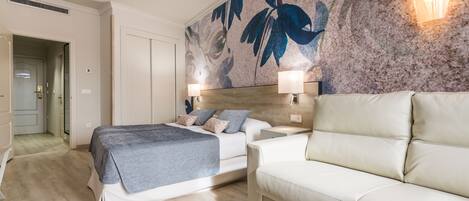 A modern bedroom with a bed, a sofa, and a wall with a floral mural.
