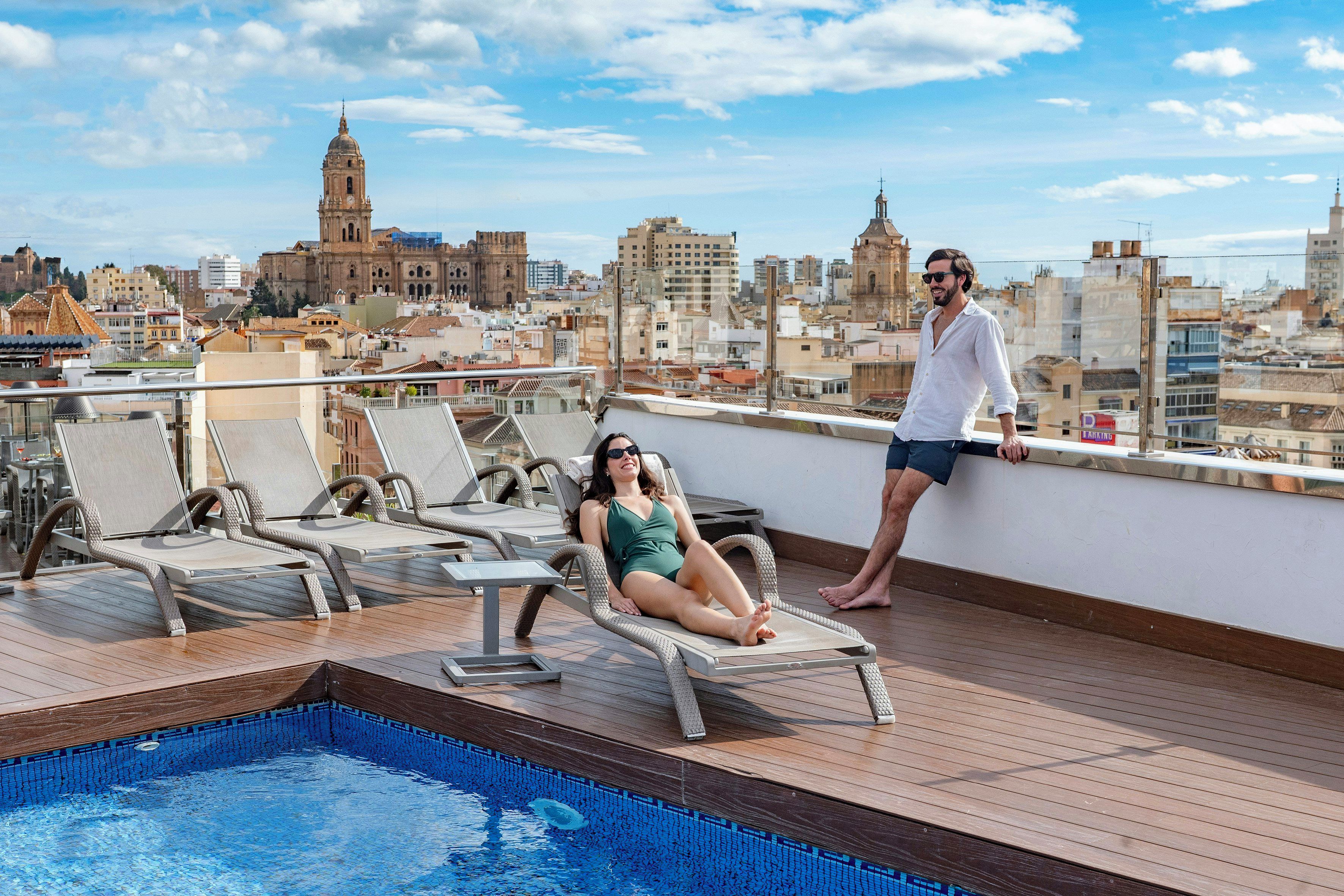 A rooftop pool area with lounge chairs and a pool.