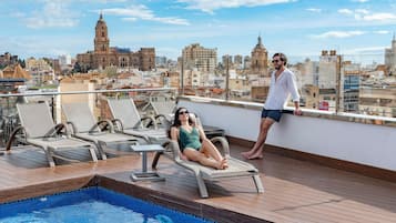 A rooftop pool area with lounge chairs and a pool.