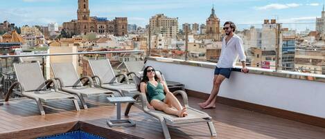 A rooftop pool area with lounge chairs and a pool.