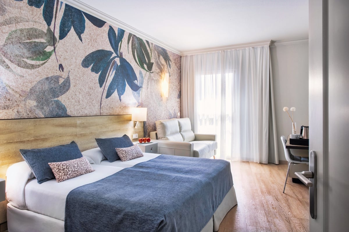 Una habitación de hotel con una cama grande, un escritorio y una silla.