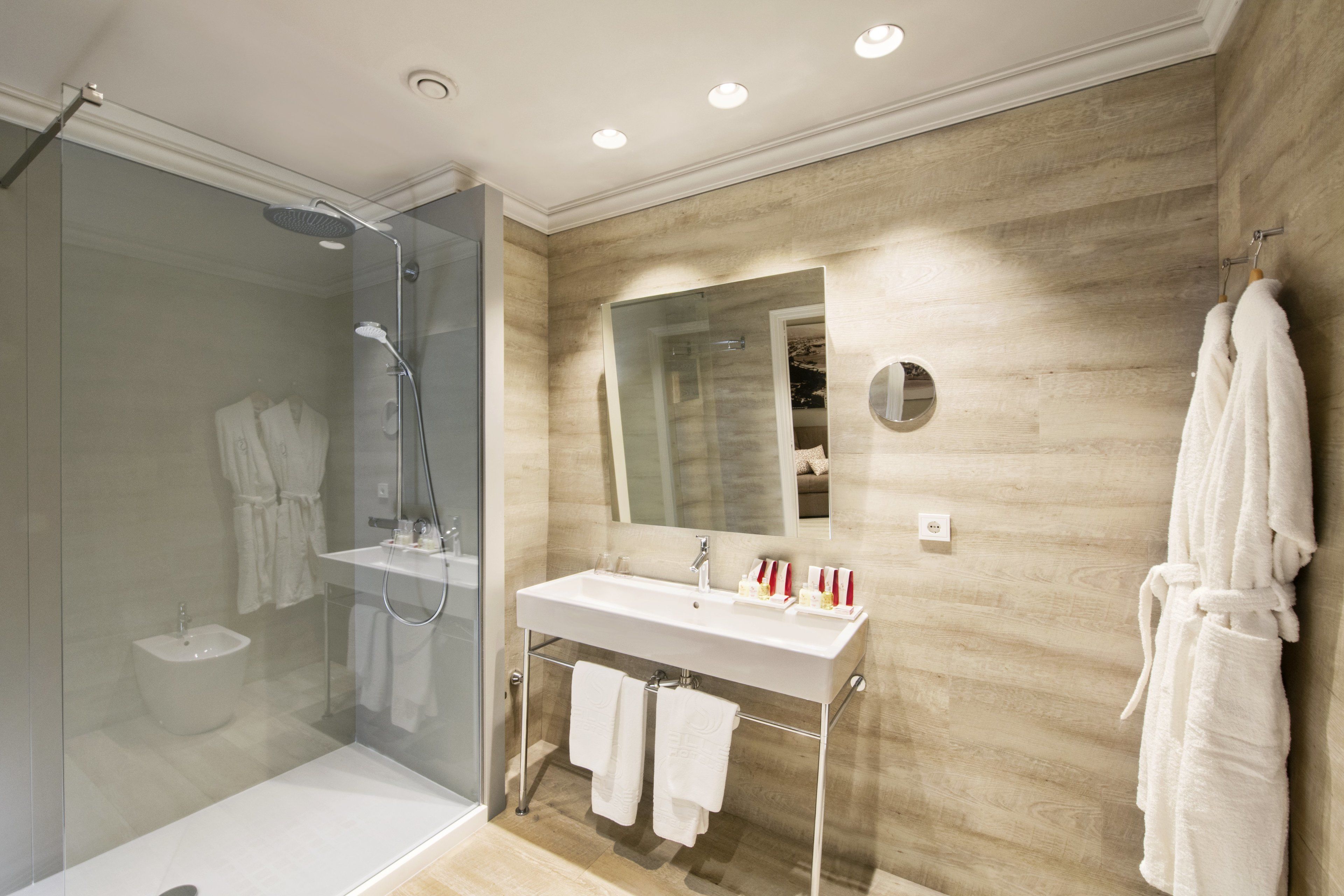 A modern bathroom with a glass shower enclosure, a white sink, and a wooden wall.