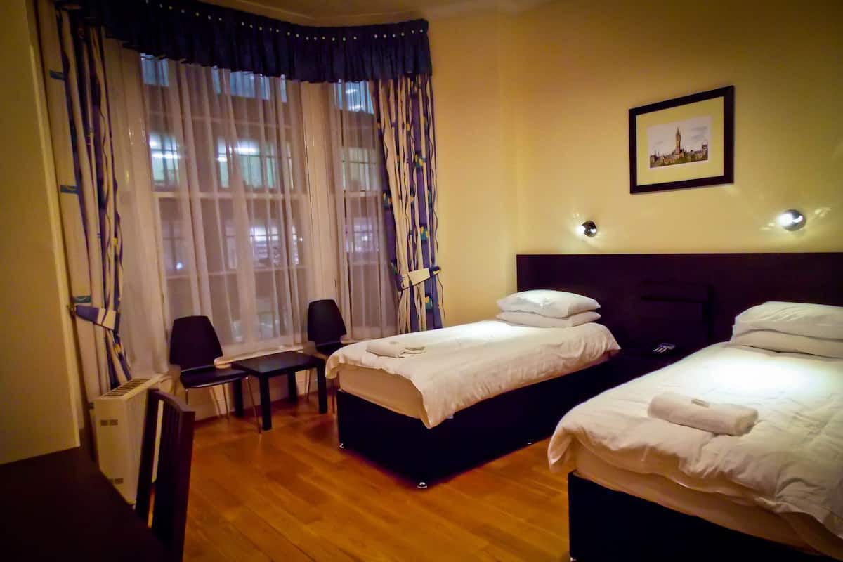 A hotel room with two beds, a desk, and a chair.