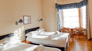 A hotel room with two beds, a small table, and a chair. - The Victorian House (Glasgow)