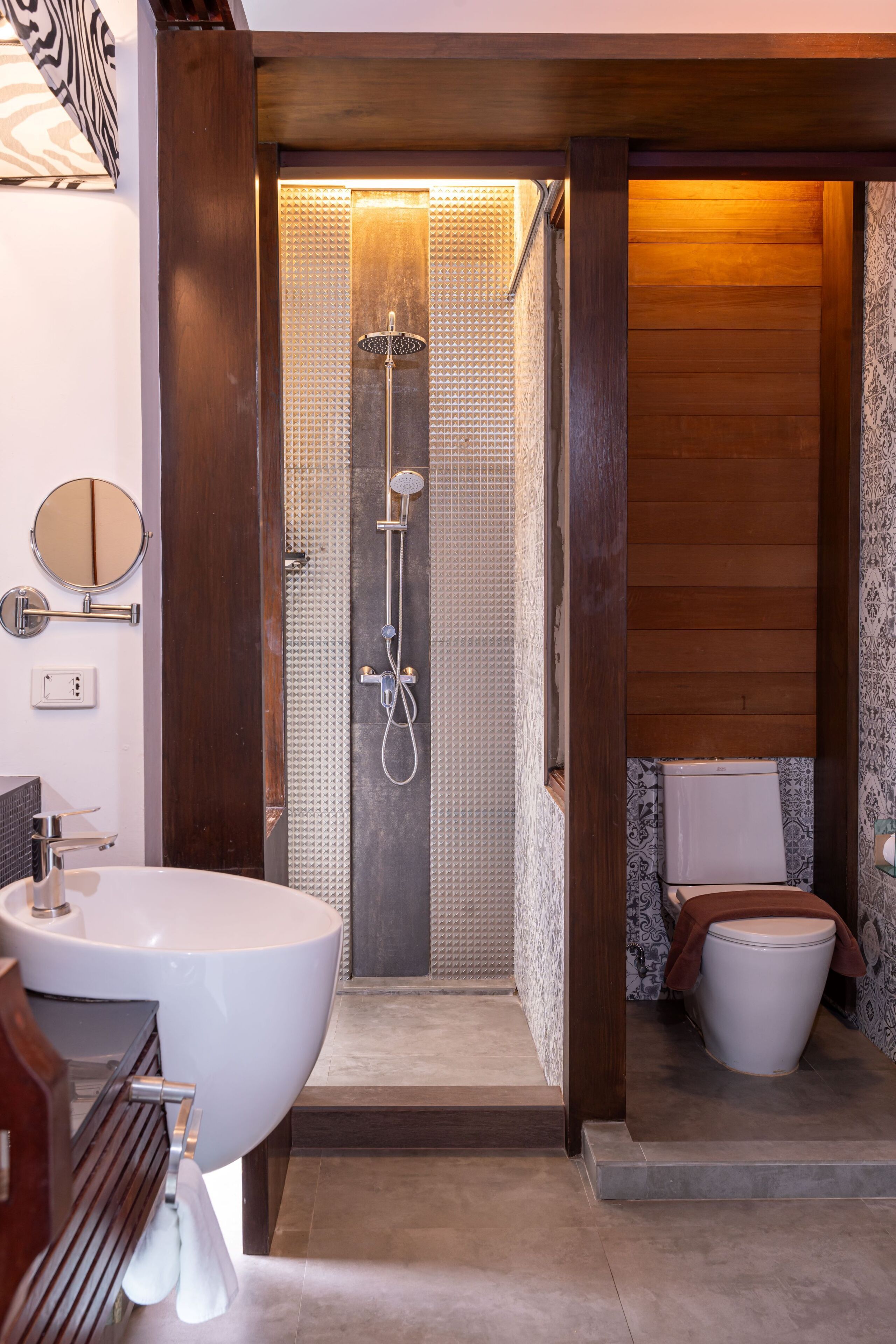 A bathroom with a large white sink, a mirror, a shower with a glass door, and a toilet.