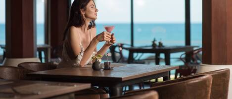 A person seated at a table with a view of the ocean.