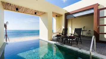 A pool area with clear water, a hammock, and a view of the ocean.