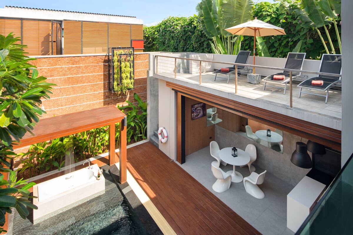 A rooftop terrace with a pool, lounge chairs, and a table with chairs.