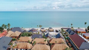 A coastal resort with multiple bungalow-style buildings, a beach, and a clear view of the ocean.