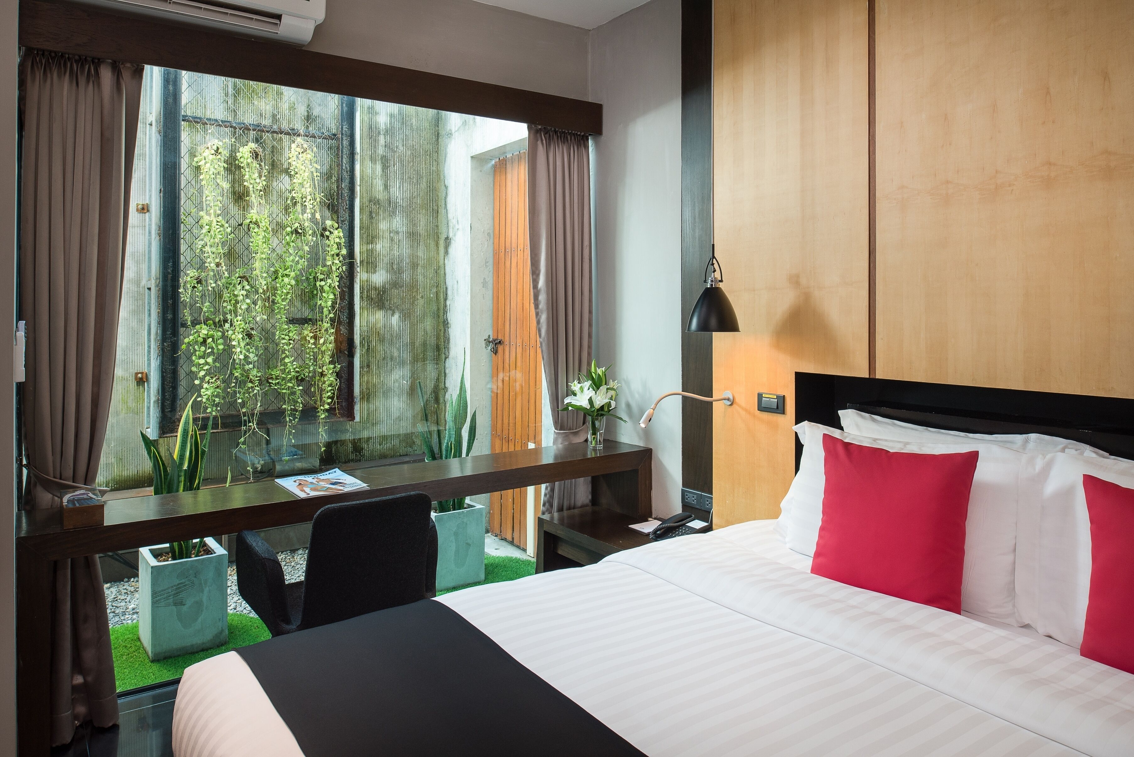 A hotel room with a bed, a desk, and a window with curtains.