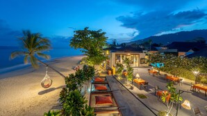 A beachfront resort with outdoor seating and a pool area.