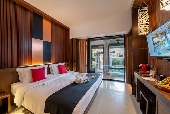A hotel room with a large bed, a wooden headboard, a television, and a breakfast bar with fruit. - Pavilion Samui Villas & Resort (Koh Samui)