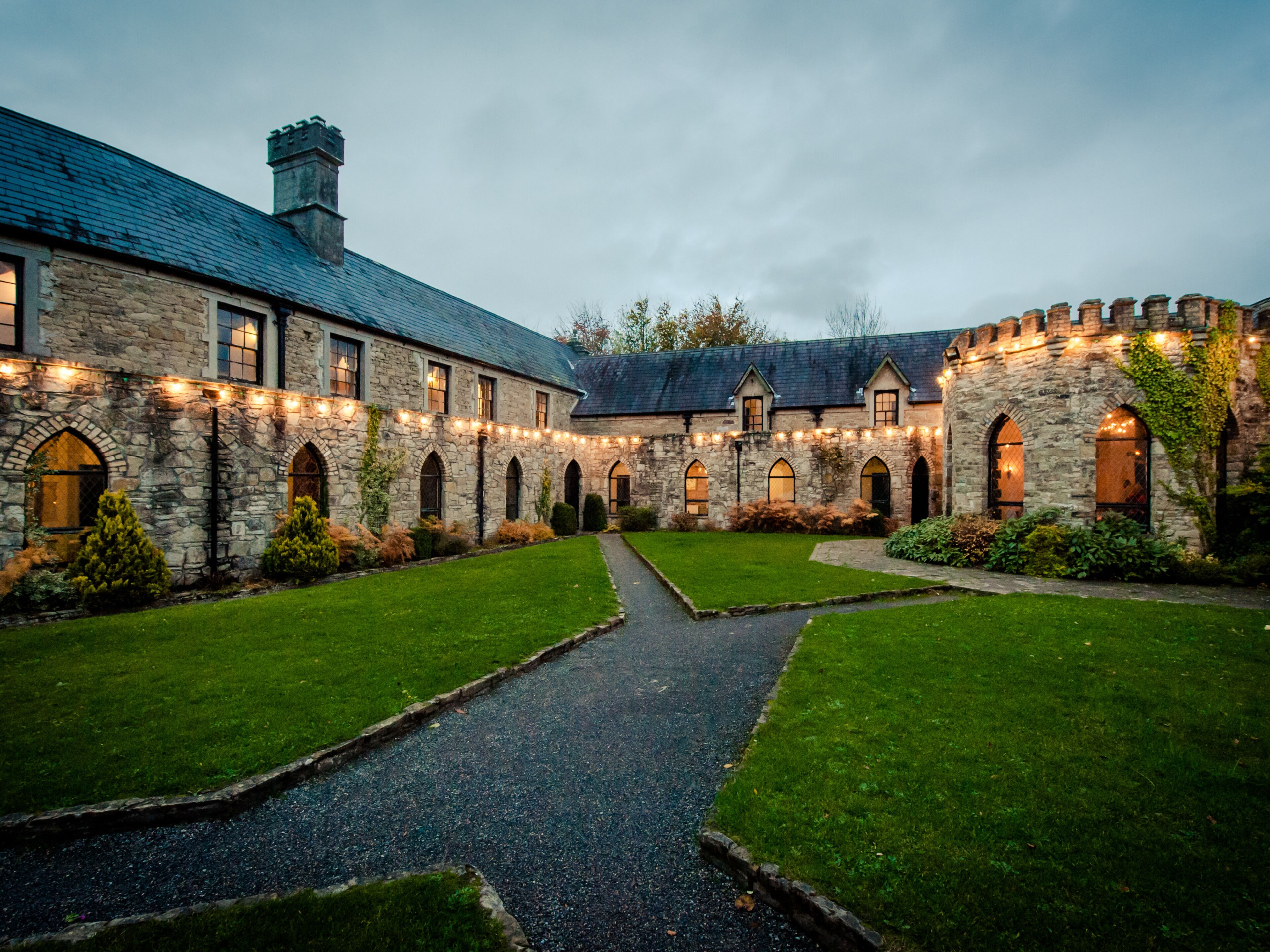 A stone building with a courtyard, arched windows, and a pathway.