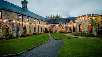 A stone building with a courtyard, arched windows, and a pathway.