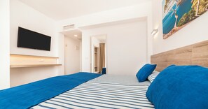 Habitación de hotel con cama, televisor de pantalla plana, un cuadro y cabecera de madera.