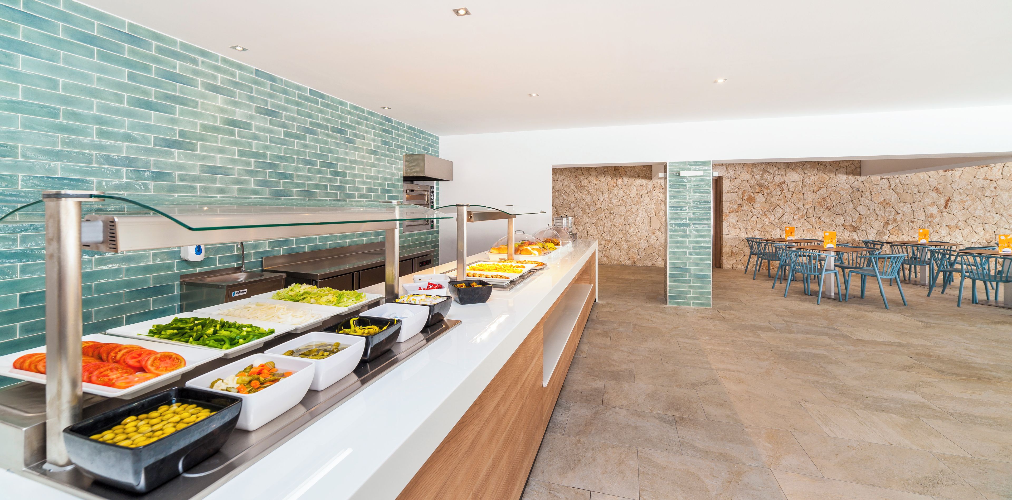 Un bufé con diferentes opciones de comida y una zona de estar con mesas y sillas.
